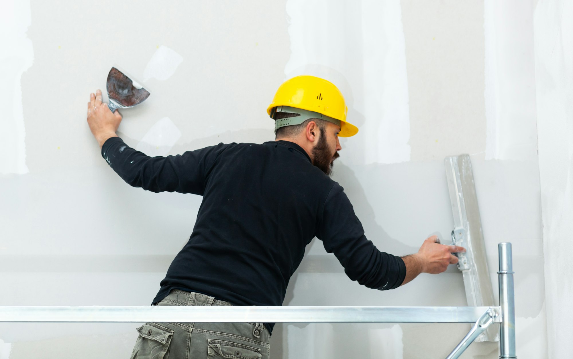 worker plastering gypsum board wall, tiling flooring plastering