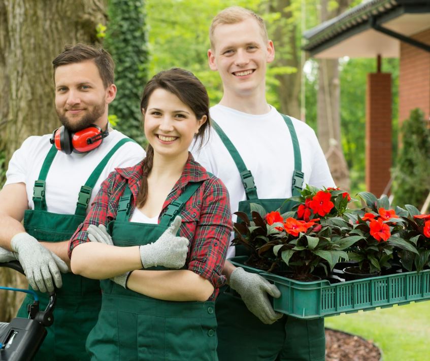 a group of people wearing overalls and holding plants